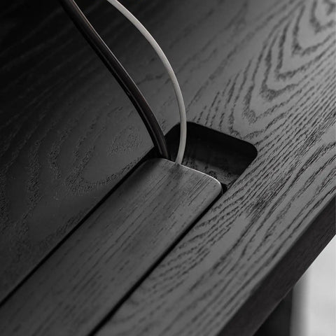 Close-up of cord management system on Super Sturdy Electric Standing Desk With Dual Storage Drawers And Whisper Quiet Lift Features A Heavy Duty Ash Wood Desktop In Crisp Matte Black.