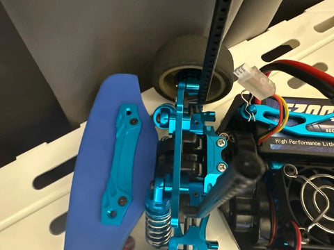 Close-up of TT02 on-road RC car upgrade part kit with aluminum drive shaft and blue CVD steering cups for Tamiya TT02 vehicle.
