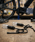 Dope 48V To 72V LED Bike Turn Signals With Bright Orange Amber Bulbs For Scooters And Ebikes That Keep You Safe On The Road With Super Clear Indicators. Two clear-lens ABS bike turn signals with wires on a workbench, for 48V-72V scooters and ebikes