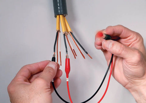 Hands using a Remote And Local Continuity Tester With Detachable Remote Probe Audible Tone Long Distance Cable Testing.