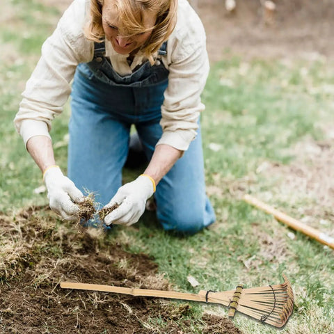 Person gardening with Solid Bamboo Garden Rake For Sandboxes And Landscaping, Lightweight Eco Friendly Yard Tool, 19.7 Inch nearby