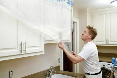 Man using Pro Grade Masking Film Kit With Static Cling 8 Rolls Of 48 In By 180 Ft Each Keeps Film In Place, flake resistant.