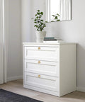 Six Piece Ginkgo Leaf Cabinet Knobs And Solid Zinc Drawer Pulls In Rustproof Brushed Gold Finish on white dresser with plant.