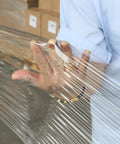 Heavy Duty Industrial Clear Stretch Wrap 4 Rolls 15 Inch Wide By 1000 Feet 80 Gauge Workhorse Grade in use, showing hand gripping stretch film.