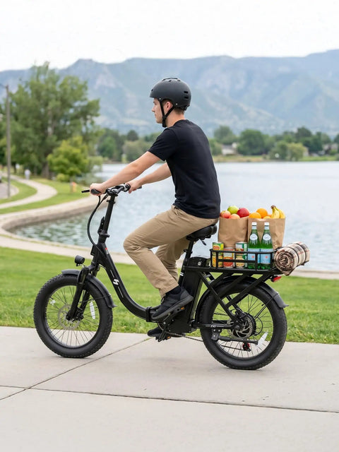 Person riding Foldable Electric Bike for Adults With 1200W Peak Motor carrying groceries near a lake path.