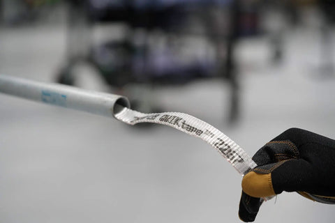 QWIKtape Pull Tape Go-To Multi Use Polyester Tape for threading and pulling wire, shown in use with conduit and glove