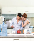 Couple in kitchen with Electric 5 Gallon Water Dispenser Pump Portable USB Rechargeable For Universal 2 To 5 Gallon Bottles Leak Proof Silicone Tube