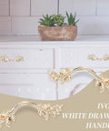 Ivory white drawer handles installed on a vintage dresser, with decorative floral design and gold accents, front view.