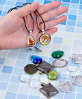Pendant Tray Jewelry Making Kit With Glass Cabochons 90 Pcs Set Including 30 Bezel Pendants 30 Cabochons And 30 Necklace Cords For DIY Necklaces And Crafting displayed.