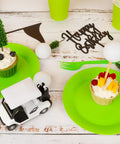 21 Piece Golf Cake Decorations Kit Featuring Mini Golf Cart Toy Acrylic Flags And Lush Green Trees For A Hella Sweet Golfer Birthday Bash and Party Table Centerpiece with cupcakes on green plates.
