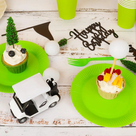21 Piece Golf Cake Decorations Kit Featuring Mini Golf Cart Toy Acrylic Flags And Lush Green Trees For A Hella Sweet Golfer Birthday Bash and Party Table Centerpiece with cupcakes on green plates.