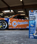 Ultra Grey RTV Silicone Gasket Maker 3 oz package in an automotive garage with a race car in the background.