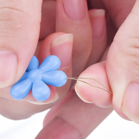 Close-up of hands using blue flower head wire loop from 30 Piece Needle Threader Set With Clear Box Multicolor Flower Head Wire Loop Threaders.