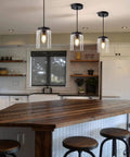 Industrial Mini Pendant Light Set With Bubble Seeded Glass Hanging Light Fixture For Kitchen Island Over Sink And Dining Room, Black Finish, 3-Pack Bundle illuminating a kitchen island.