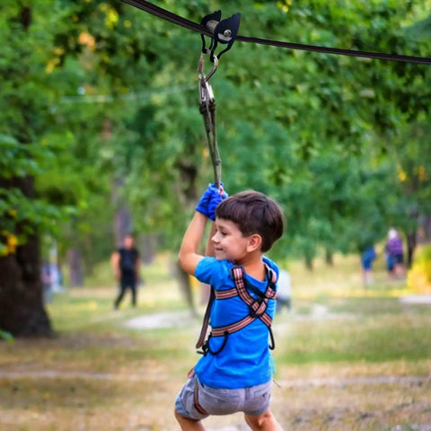 Child using Heavy Duty Zip Line Pulley Kit With Six Steel Rollers For Backyard Adventure, easy install, supports up to 440 lbs