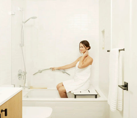 Person using 30 Inch Crescent Curved Shower Grab Bar Built Tough In Polished 304 Stainless Steel One Piece Welded Cap 250 Pound Weight Capacity Includes Mounting Screws For Easy Install in a white bathroom.