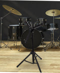 Slick Black Tripod Drum Stand With Heavy Duty Snare Rack And Practice Pad Holder Featuring Adjustable Heights, in front of a drum set.