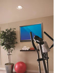 Room with recessed light ventilation fan with adjustable mounting brackets, white finish on 2x8 ceiling, exercise bike, and TV.