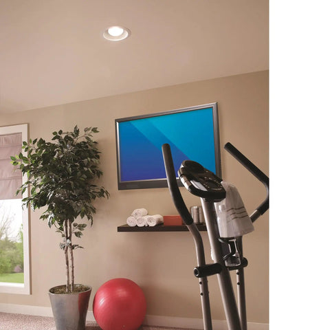 Room with recessed light ventilation fan with adjustable mounting brackets, white finish on 2x8 ceiling, exercise bike, and TV.