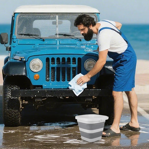 Man washing car by beach with 5L Collapsible Cleaning Bucket With Triple Reinforced Frame For Camping And Outdoor Use beside him