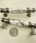 Two decorative cabinet pulls with marble-look design and silver hardware next to a quarter for scale.