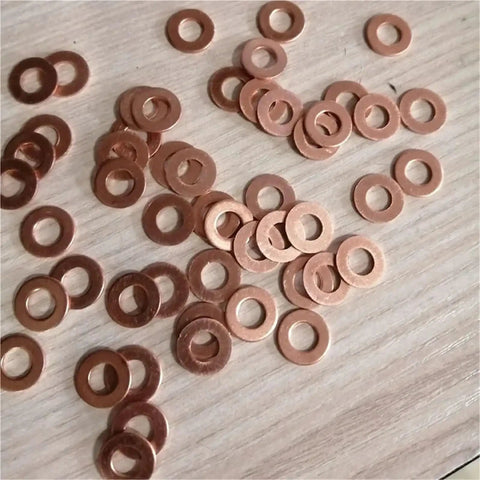 Solid Annealed Pure Copper Flat Washers Kit Vibrant Orange M5 To M20 With 1Mm And 2Mm Thickness Ideal For Hardcore Auto Repair Where You Need Reliable Sealing Performance On Heavy Load Application Without Struggling Too Much At All. copper washers spread on a wood surface