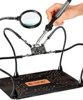 Must Have Helping Hands Soldering Station with 5X magnifying glass in use, magnetic supports, and lightweight clips holding circuit board