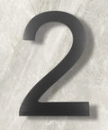 10 Inch Aluminum Floating House Number 2 in Black With Brushed Finish for Slick Curb Appeal Durable Rustproof Street Address Sign Large Contemporary Wall Mount Address Plate on marble surface.