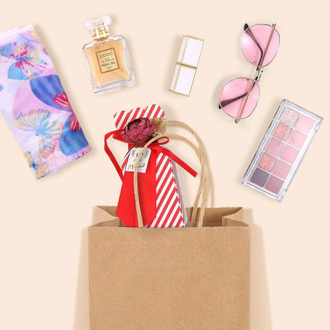 Brown Kraft Gift Bags With Handles 5.25x3.75x8 Inches 20 Pack filled with cosmetics, glasses, and a gift, flat lay view.