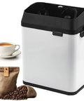 Automatic Portafilter Cleaner And Electric Knock Box Set With Two 58 Mm Scrapers And Pro Brush For Slick Daily Espresso Care and No Stress Backyard Barista Setup In Silver with cup of coffee.