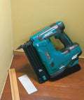 18V LXT Cordless 2-Inch Brad Nailer With 110-Nail Magazine in corner, trim work setup, gray handle, teal body