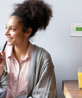 Woman sitting near 7 Day Programmable Thermostat With Backlit Digital Display And Precise Temperature Control To Within 1 Degree Fahrenheit