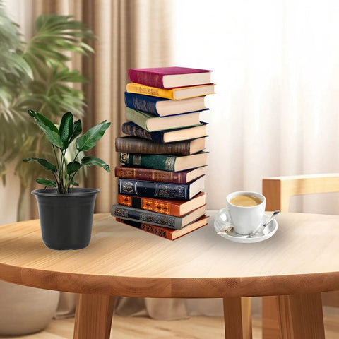 Stack of books, cup of coffee, and plant on a wooden table in a cozy room with curtains in the background.