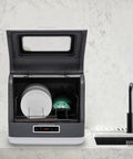 Compact Portable Countertop Dishwasher Featuring Three Wash Cycles and a Straight Up No Install Faucet Setup, showing plates inside.