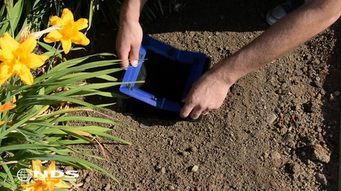 Person installing Square Catch Basin Drain Filter For No Clog Drainage Systems in a garden, removable filter for 12 inch basins.