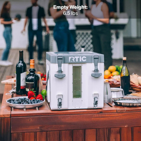 RTIC cooler on wooden table with fruits and wine bottles at outdoor gathering, showcasing its portability and design for events
