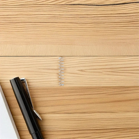 Upgrade Your Pens With A 40pc Ballpoint Pen Spring Kit Made From Durable Stainless Steel For Smooth Writing, Quick Refill Replacement And Total Comfort So You Can Write Fast Like A Boss At School Or Work Today. stainless steel pen spring beside black ballpoint pen on wood