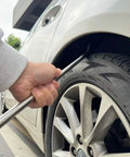 Using Beast 91-Piece Paintless Dent Repair Kit rod on car wheel arch for dent removal.