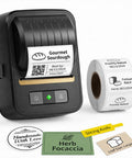 Awesome Bluetooth Label Maker Machine Printing On White Color Clear Thermal Labels With Tape For Home Business Organization Crisp Graphics No Ink Needed 2 Inch Wide Portable Handy Tech Gadget next to labels for gourmet sourdough and herb focaccia.