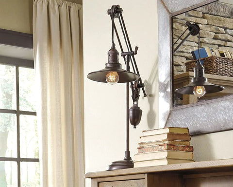 Urban Industrial 29.5 Inch Metal Desk Lamp With Adjustable Arm And Shade Bronze Finish next to vintage books against a window
