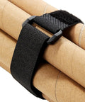Close-up of a black hook and loop nylon strap from the Twenty Pack Reusable Cable Ties And Straps 12x1 Inch Adjustable Hook And Loop Nylon Fasteners For Cable Management, Multi Purpose Wire Organizer Straps For Home Office Garage And Do It All Projects, securing cardboard tubes.
