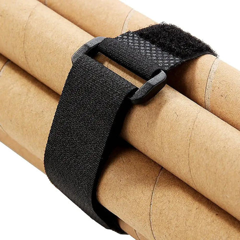 Close-up of a black hook and loop nylon strap from the Twenty Pack Reusable Cable Ties And Straps 12x1 Inch Adjustable Hook And Loop Nylon Fasteners For Cable Management, Multi Purpose Wire Organizer Straps For Home Office Garage And Do It All Projects, securing cardboard tubes.