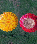 Top view of flower-shaped metal bird baths with seeds on grass, part of the Flower Bird Bath With Metal Stake Set Of Four For Outdoor Gardens A Charming Yard Decor For Bird Lovers Each Bath Measures 7.1 Inches In Diameter And 1.3 Inches Deep With Easy To Install Stakes.