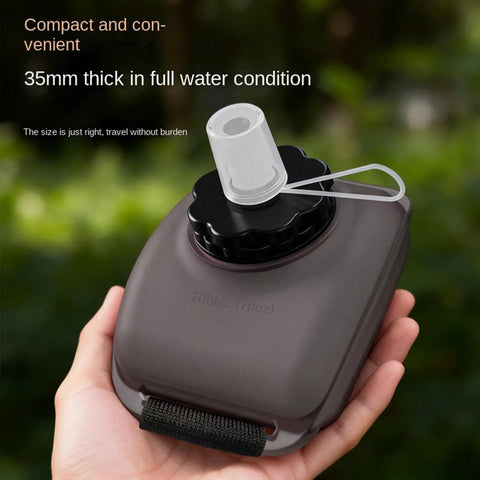 Hand holding a 200ml Wrist Water Bottle On The Go 200ml Leak Proof No Spill Hydration Gear With Silicone Strap showing mouthpiece.
