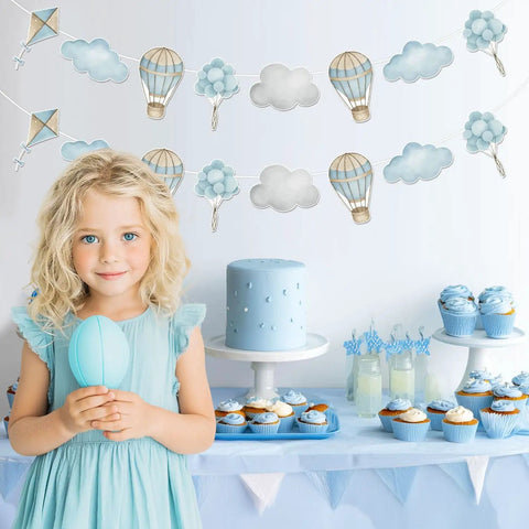 Child holding balloon with Blue Hot Air Balloon Banner Set For Baby Shower And Birthday Party Adventure Awaits Garland in background
