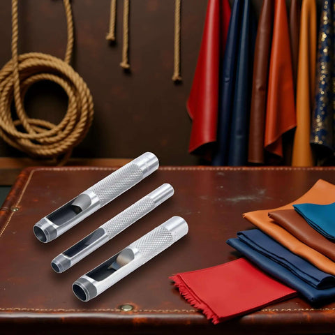 Three-Piece Grommet Hole Punch Set For Leatherworking, Heavy Duty Steel Hollow Punches on leather surface with fabric rolls nearby.