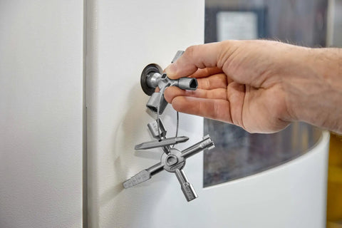 Hand using TwinKey Multifunctional Spanner Kit With Magnetic Eight Arm Two By Four Way Spider Keys for shut-off system operation.
