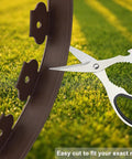 Scissors cutting 40 Ft Brown Landscape Edging Kit With 40 Spiral Stakes, No Dig Plastic Border Roll on grass
