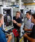 Image of technicians discussing machine repairs, featuring Straight-Up Red Out Of Service Tags With Galvanized Wire Ties, 200 Pack Heavy Duty Laminated Repair Required Lockout Signs For OSHA Wall Mounting Industrial Machine And Valve Inspection Safety Gear.