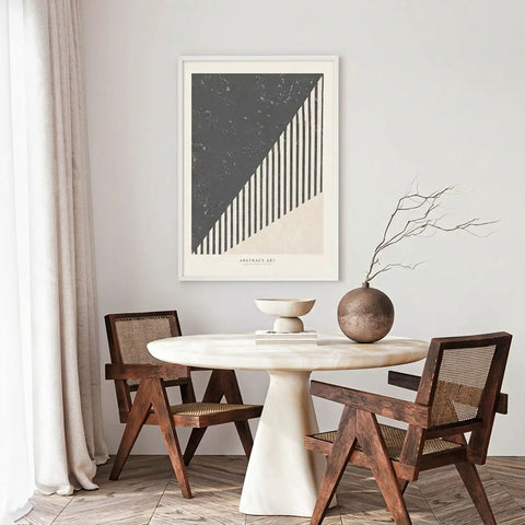 Modern dining area featuring abstract art print, round marble table, wooden chairs, and decorative vase.